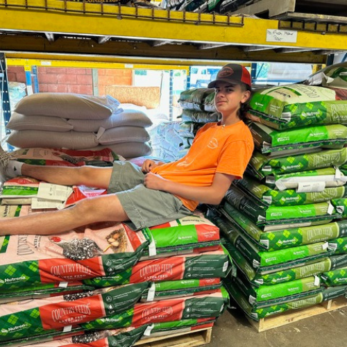 Roger's staff laying on bags of feed inside of the store