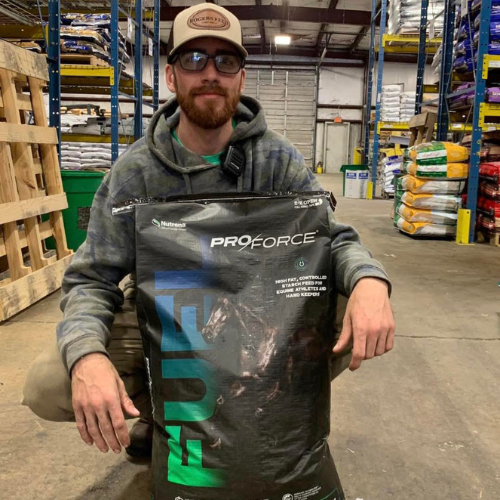 Roger's staff squatting behind a bag of horse feed inside of the store