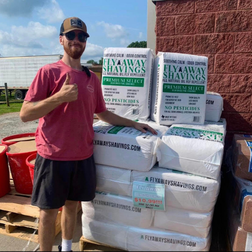 Roger's staff standing in front of hay bales with a thumbs up