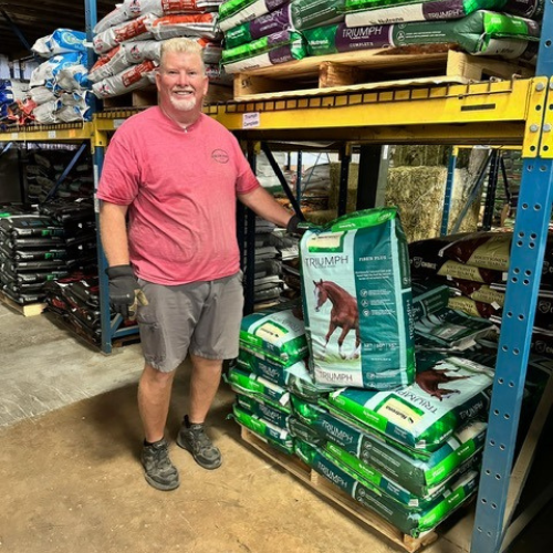 Roger's staff standing in front of bags of horse feed inside of the store