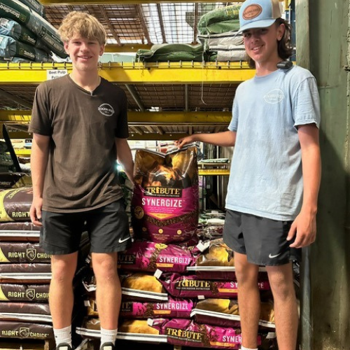 Roger's staff standing in front of bags of horse feed inside of the store