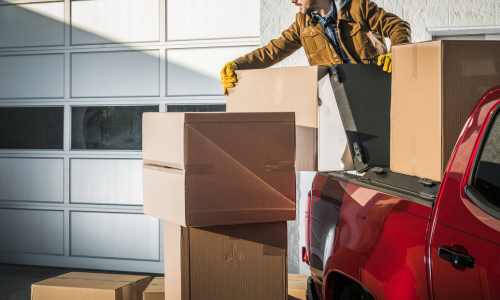 Man putting boxes in back of a red pickup truck