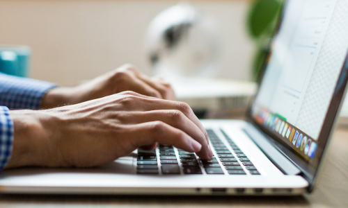 Hands typing on a laptop